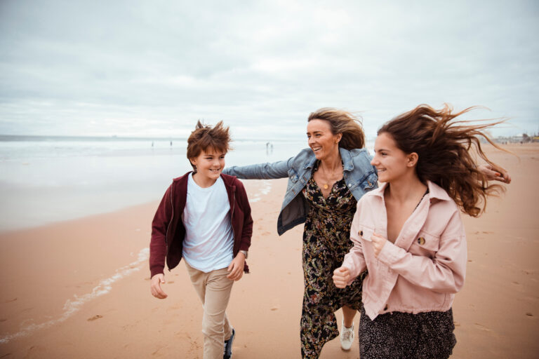 Mother walking on the beach with her children, symbolizing the journey of healing and rebuilding trust after the trauma of divorce and parental infidelity.